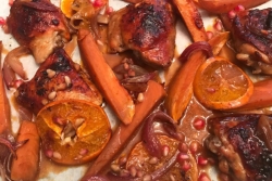 Orange pomegranate chicken lying on a sheet pan 